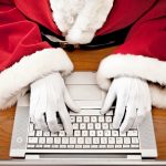 Las manos de Santa Claus digitando en una laptop.