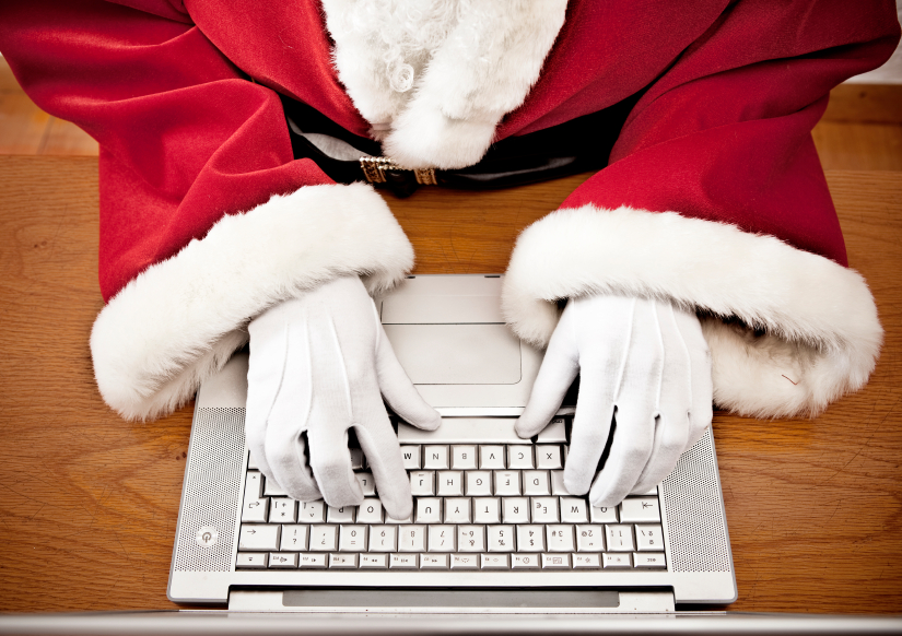Las manos de Santa Claus digitando en una laptop.