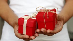 Un hombre mostrando dos regales navideños.