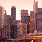 Skyline of modern skyscrapers against a sunset sky with warm hues