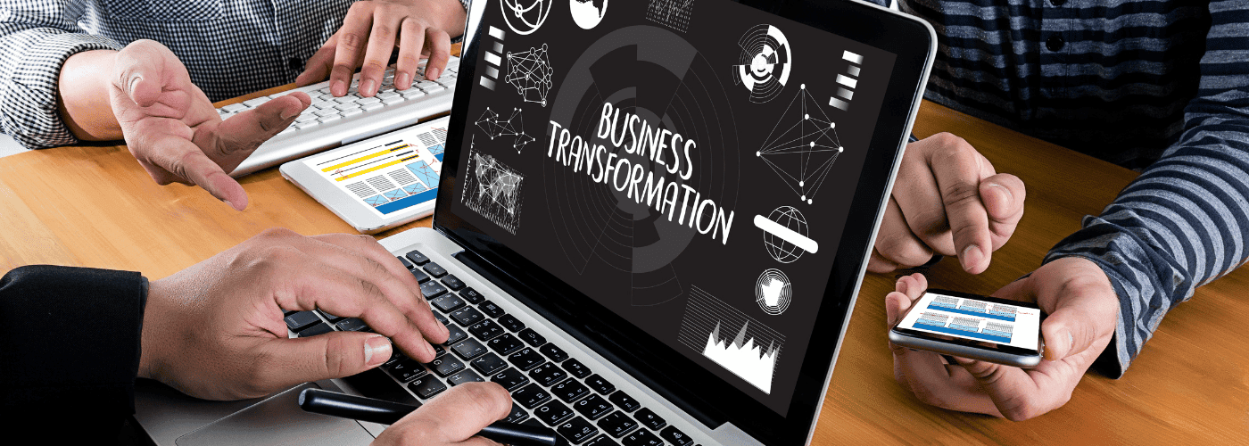 Varias personas alrededor de una laptop hablando sobre transformación digital.